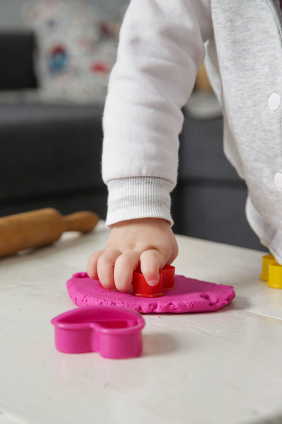 Toddler girl playing with modelling clay. Play dough allows kids to develop fine motor skills, strengthen fingers, hands and wrists and to be naturally curious and explore the world using their senses - Photo, Image