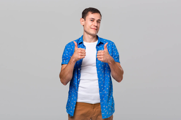 Hombre sonriente confiado mostrando el pulgar hacia arriba expresando evaluación positiva
 - Foto, imagen