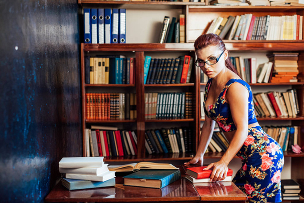 una mujer se sienta en un escritorio libro bibliotecario educación
 - Foto, Imagen
