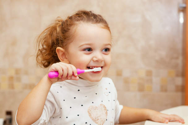Cute little girl cleaning tooth with brush. - Фото, изображение