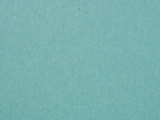 The surface of a sheet of cardboard is blue or aquamarine. Light background or wallpaper. Rough paper texture with cellulose fibers and stains. Reduced contrast. View from above. Close-up - Foto, Imagen