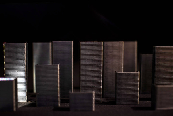 Abstraktion einer simulierten Stadt aus Klammern, die Wolkenkratzer mit dunklem Hintergrund und Schatten bilden. verschwommene dunkle Stadt. - Foto, Bild