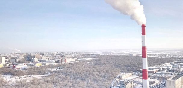 chimenea humeante de una central térmica en el fondo de la ciudad de invierno
. - Foto, Imagen