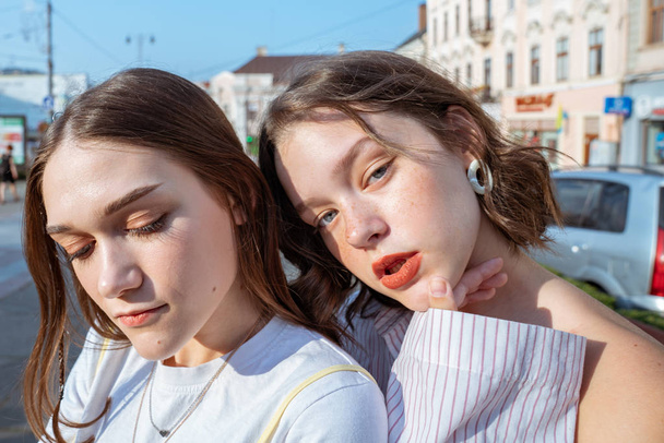 Close up portrait of the beautiful hipster girls with brunette hair, red lips and green eyes enjoying summer sunny days in the city - Photo, Image