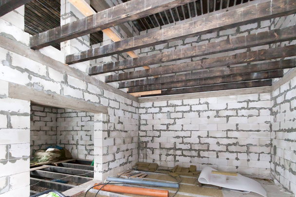 Le chantier de construction de l'intérieur du bâtiment résidentiel en cours de construction à nouveau mur de briques blanches maison unifamiliale avec poutres en bois
. - Photo, image