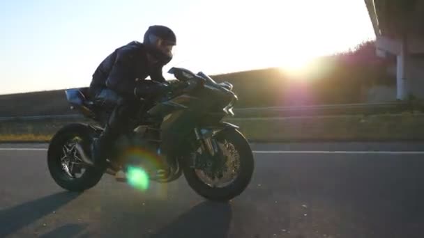 Mies ratsastaa moderni urheilu moottoripyörä moottoritiellä auringonpurkaus taustalla. Moottoripyöräilijä kilpa hänen moottoripyörä Country Road. Kaveri ajaa pyörällä matkan aikana. Vapauden käsite. Hidastus - Materiaali, video