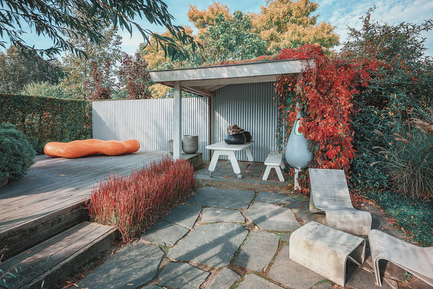 Jardin branché avec terrasse et surplomb, décoré avec mobilier de jardin tendance et jardinières dans un jardin d'automne
 - Photo, image