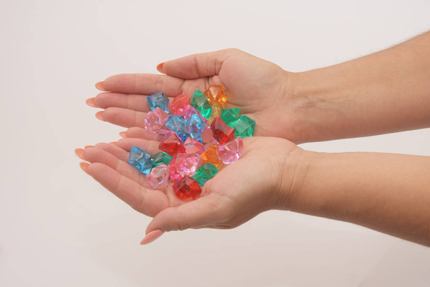 Női kéz szorított tartsa sokszínű üveg kavicsok egy könnyű háttér. Ékszerek és játékok nők és gyermekek számára. - Fotó, kép