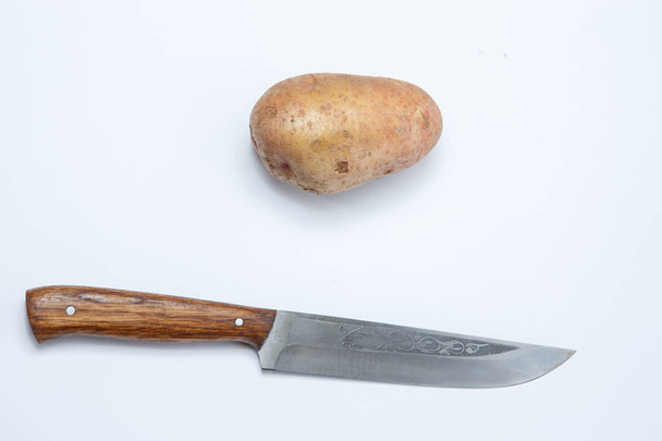 Cuchillo con mango de madera con patatas
 - Foto, Imagen