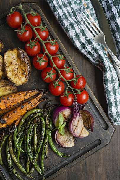 Grilled vegetables on a cutting board on a dark wooden background. Dark wooden background. - Photo, Image
