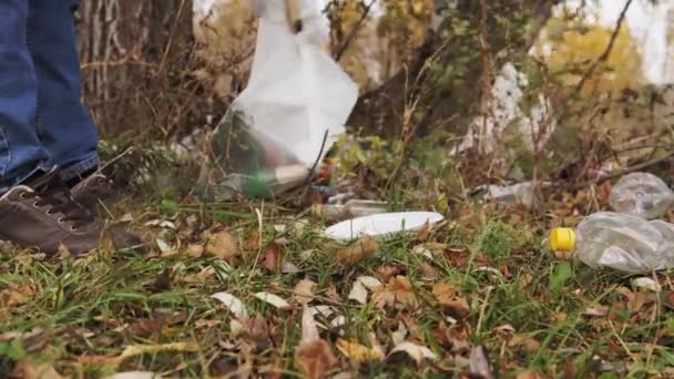 Ökológiai koncepció, műanyag hulladékgyűjtés a természetben. Felelős férfi önkéntes összegyűjti a szemetet egy táskába, fa fogóval, közelről. - Felvétel, videó