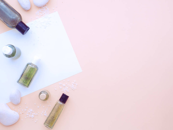 Fresh green natural cosmetics, body shower gel or liquid handmade soap and spa stones and salt isolated on a pastel pink background. Flat lay, top view, copy space - Valokuva, kuva