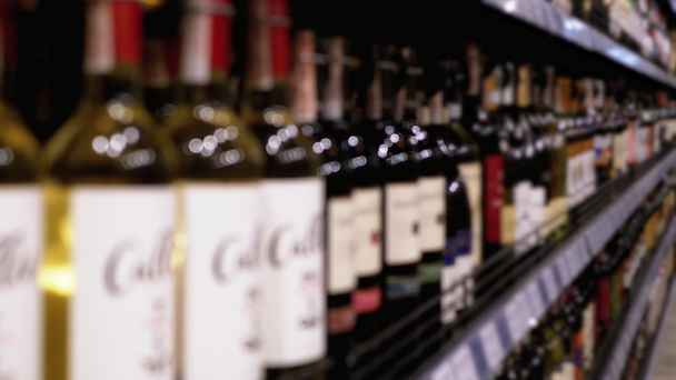 Alkoholverkauf im Supermarkt. Zeilen und Regale mit Flaschenweinen mit Preisschildern an einem Schaufenster in Unschärfe - Filmmaterial, Video