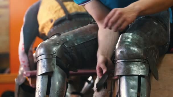Knights koulutus - mies laittaa metallia suojaava haarniska polvillaan
 - Materiaali, video
