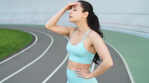 Ελκυστική δρομέας γυναίκα λαμβάνοντας υπόλοιπο μετά από τρέξιμο προπόνηση σε πίστα - Πλάνα, βίντεο