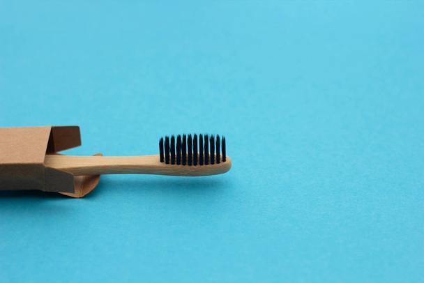 Une brosse à dents en bois de bambou avec des poils naturels dans une boîte en carton repose sur un fond bleu. Aucun gaspillage. Concept de conservation de la Terre
 - Photo, image