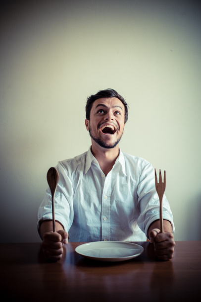 молодой стильный мужчина в белой рубашке ест во время еды
 - Фото, изображение