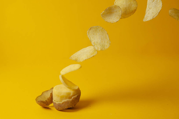 Kartoffelchips fliegen auf einem gelben Hintergrund, der Prozess der Herstellung von Chips, Fast Food Schweben - Foto, Bild