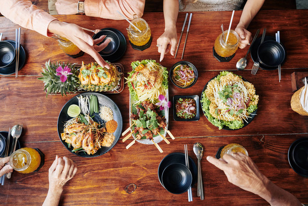伝統的なアジア料理や飲み物で夕食をとる人々のグループ、上からの眺め - 写真・画像