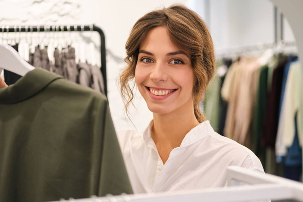 Young pretty stylish woman joyfully looking in camera working in modern showroom  - Photo, Image