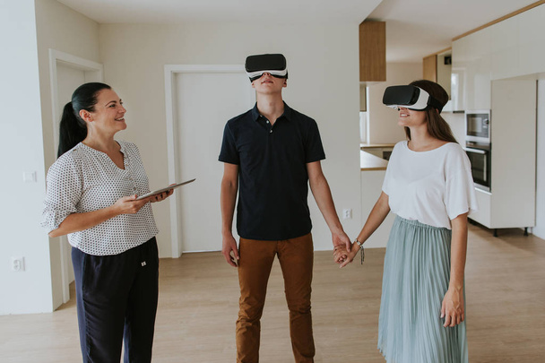 Kiinteistönvälittäjä nuori pari yllään VR kuulokkeet uudessa asunnossa
. - Valokuva, kuva