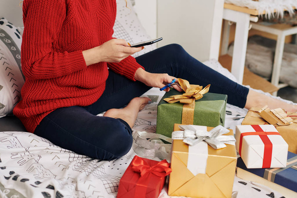 Cropped image of young woman taking photo for social media when wrapping Christmas presents - Фото, изображение