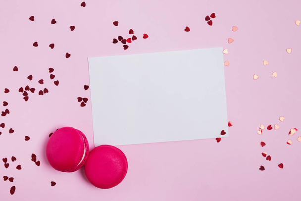 Blank paper, macarons and heart shaped confetti on pink background - Valokuva, kuva