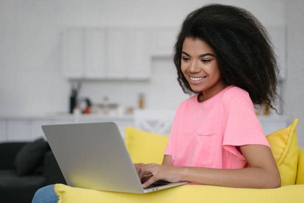 Портрет щасливої афроамериканської письменниці-переписучки, яка працює в інтернеті, сидячи вдома. Успішний бізнес і кар'єра. Гіпстер за допомогою ноутбука друкує на клавіатурі. - Фото, зображення