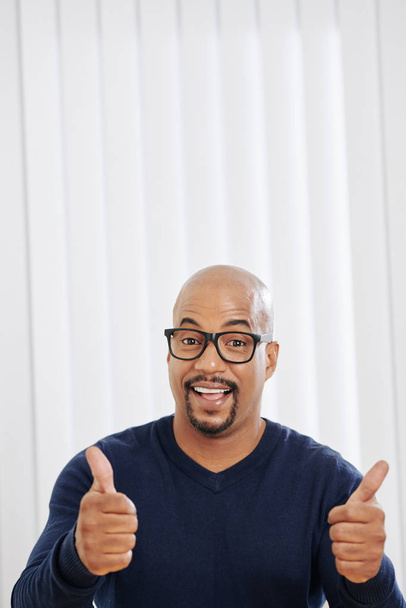 Портрет радісного збудженого лисого чоловіка в окулярах, що показує обидва великі пальці вгору
 - Фото, зображення
