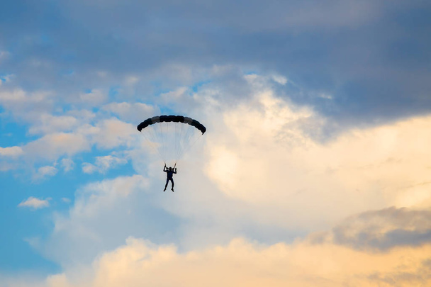 Parachutist falling from the sky in evening sunset dramatic sky. Recreational sport, Paratrooper silhouette on colored sky. - Foto, Imagen