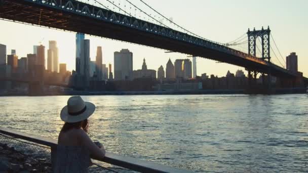 Młoda kobieta na moście w Nowym Jorku o zachodzie słońca - Materiał filmowy, wideo