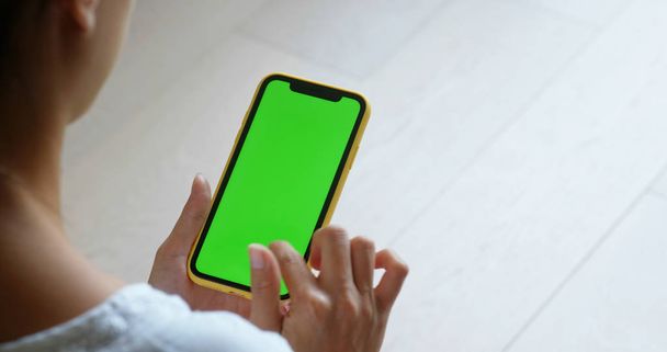 Mujer uso de teléfono celular con pantalla verde en casa
 - Foto, Imagen