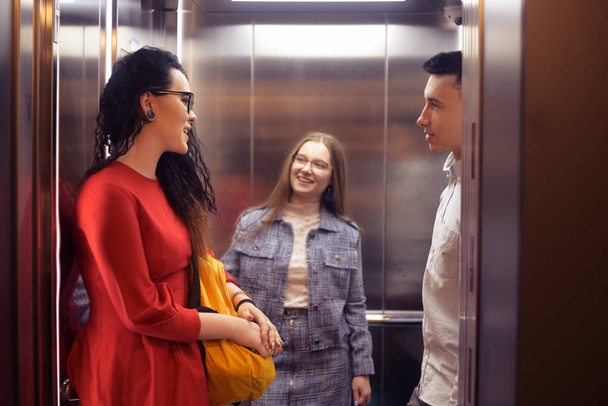 Las chicas y el tipo van en el ascensor. Estudiantes en el elev
 - Foto, Imagen