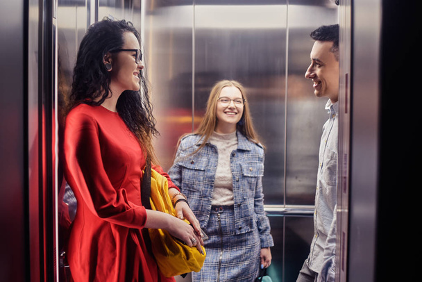 The girls and the guy ride in the elevator. Students in the elev - Foto, afbeelding