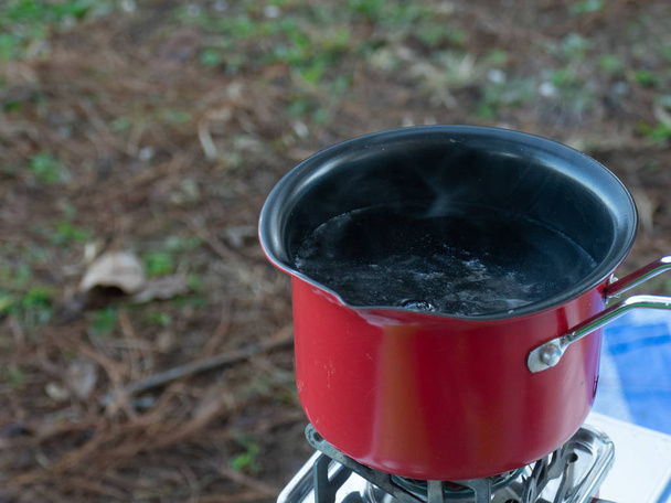 赤い鍋でお湯を沸かす. - 写真・画像