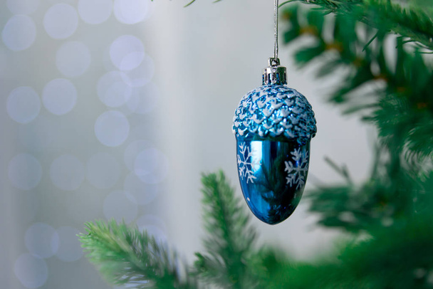Close-up Christmas decoration-bauble, fir cone blue hanging on a green Christmas tree tree on the background of bokeh. New year winter background. - Foto, afbeelding