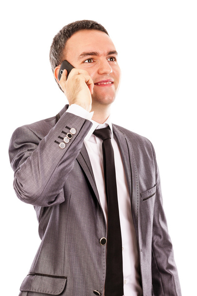 Happy young businessman talking at the phone and looking up - Foto, Imagem