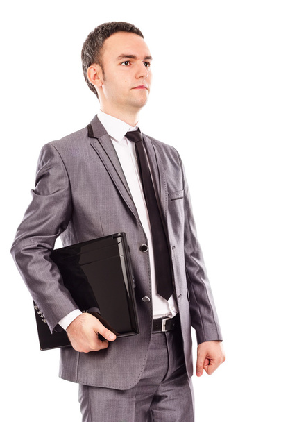Portrait of a young businessman holding a laptop under his arm - Photo, image