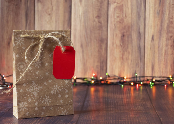 Cadeaus zijn verpakt in kraftpapier en gebonden met satijnen lint op een houten achtergrond in een kerststijl met een slinger - Foto, afbeelding