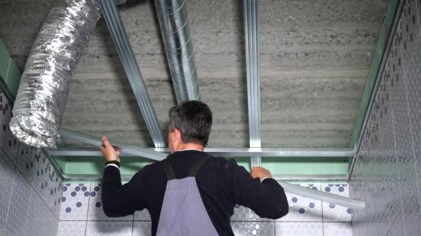 Εξειδικευμένος εργάτης στερεώνει τα προφίλ οροφής σε νέο επίπεδο δωμάτιο - Πλάνα, βίντεο