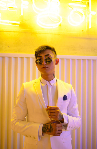 young Asian man in a white suit on a background of neon lights - Foto, immagini