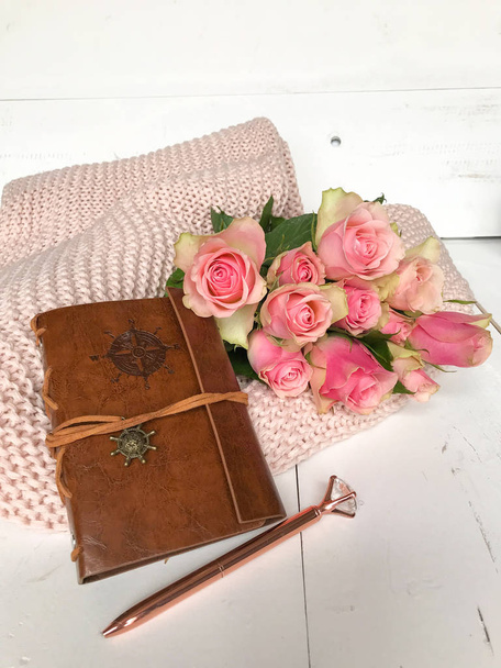 Rosas rosadas y un cuaderno de cuero sobre una manta rosa
 - Foto, imagen