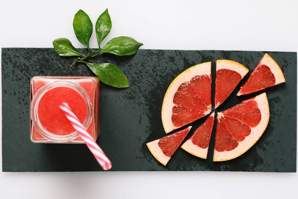 Fresh grapefruit juice in glass and sliced grapefruites on the slate plate - Foto, afbeelding