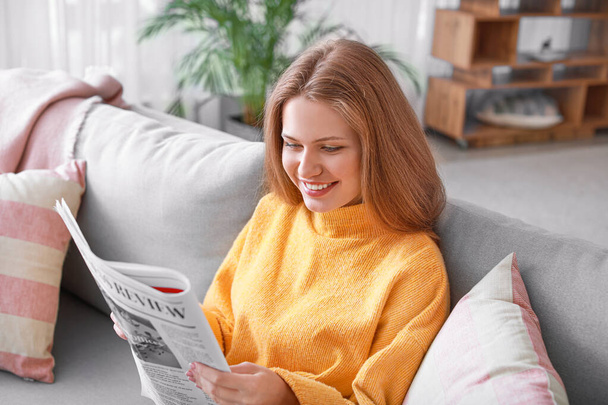 Young woman reading newspaper at home - Foto, imagen