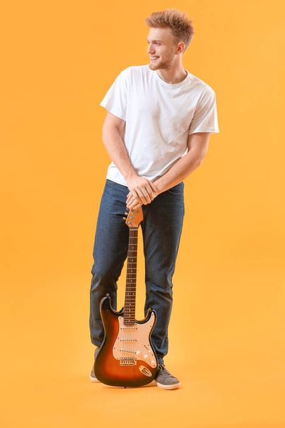 Handsome man with guitar on color background - 写真・画像