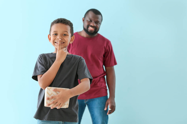 Porträt eines kleinen afrikanisch-amerikanischen Jungen mit Geschenk für seinen Vater auf farbigem Hintergrund - Foto, Bild