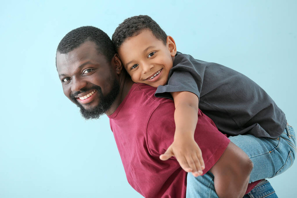 Portrait of African-American man with his little son on color background - Photo, Image
