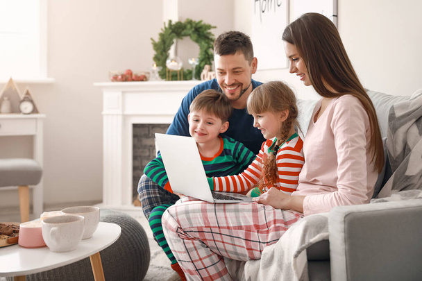 Ευτυχισμένη οικογένεια με φορητό υπολογιστή που ξεκουράζεται στο σπίτι - Φωτογραφία, εικόνα
