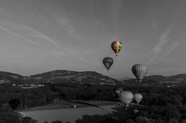 Teils farbenfrohe Heißluftballons starten in grau  - Foto, Bild