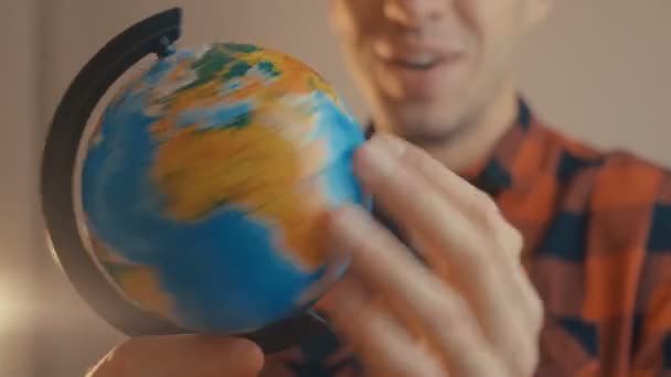 Young male holding globe. Man spinning a globe and pointing on it. Traveling concept. - Footage, Video